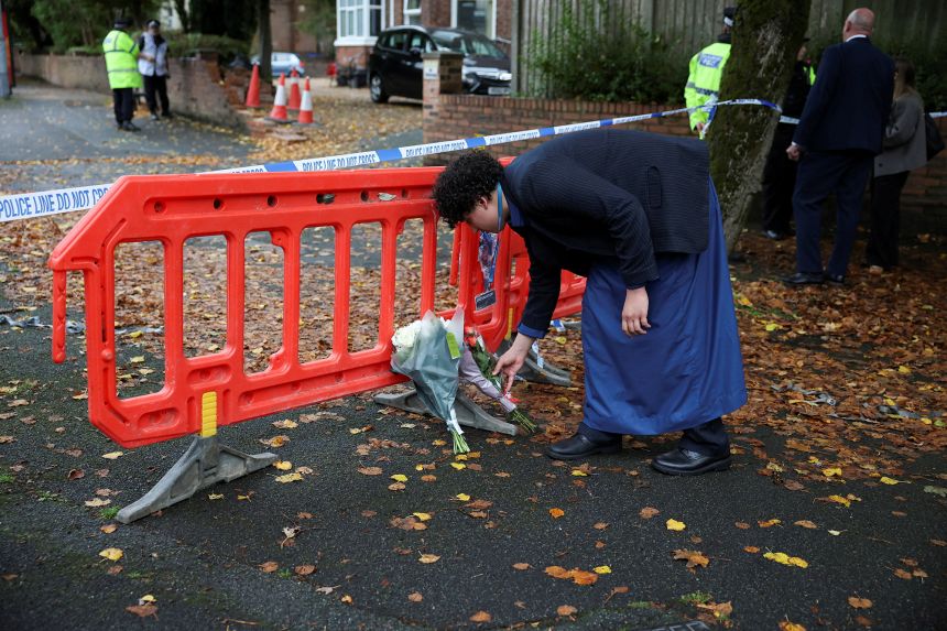 A person lays flowers at the scene outside the Manchester synagogue, on October 3, 2025, where multiple people were killed on Yom Kippur in what police have declared a terrorist incident, in north Manchester.