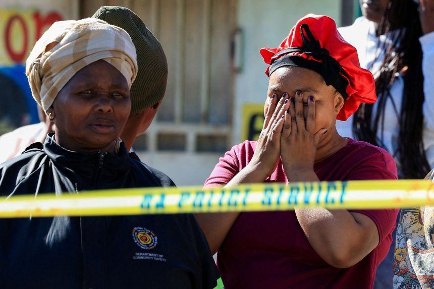 People react at the site of a shooting in Lwandle, South Africa, on September 27.