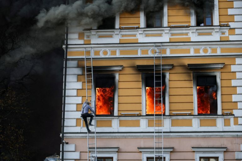 Ihor Malchevsky, 69, a deputy department head at Ukraine’s National Academy of Sciences, uses a ladder as flames rise from an administrative building hit by a Russian jet-powered drone attack, in Kyiv, Ukraine, September 28, 2026
