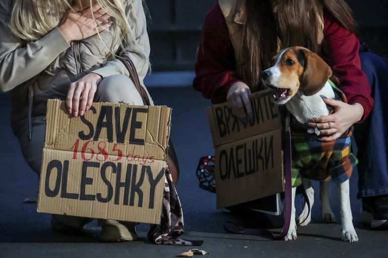 A dog looks on while women hold posters as they participate in a rally demanding the establishment of a humanitarian corridor to evacuate Ukrainian civilians from the town of Oleshky in Kherson region, amid Russia's attack on Ukraine, in Kyiv, Ukraine October 6, 2026. REUTERS/Alina Smutko TPX IMAGES OF THE DAY