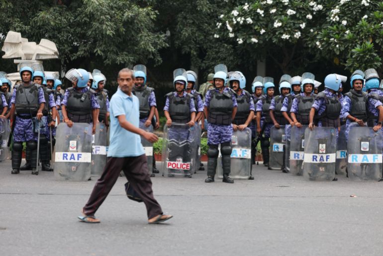 A man walks past members of the Rapid Action Force (RAF) standing guard ahead of a protest planned by the Cockroach Janta Party (CJP) seeking the resignation of India’s Chief Election Commissioner Gyanesh Kumar, in New Delhi, India, October 10, 2026