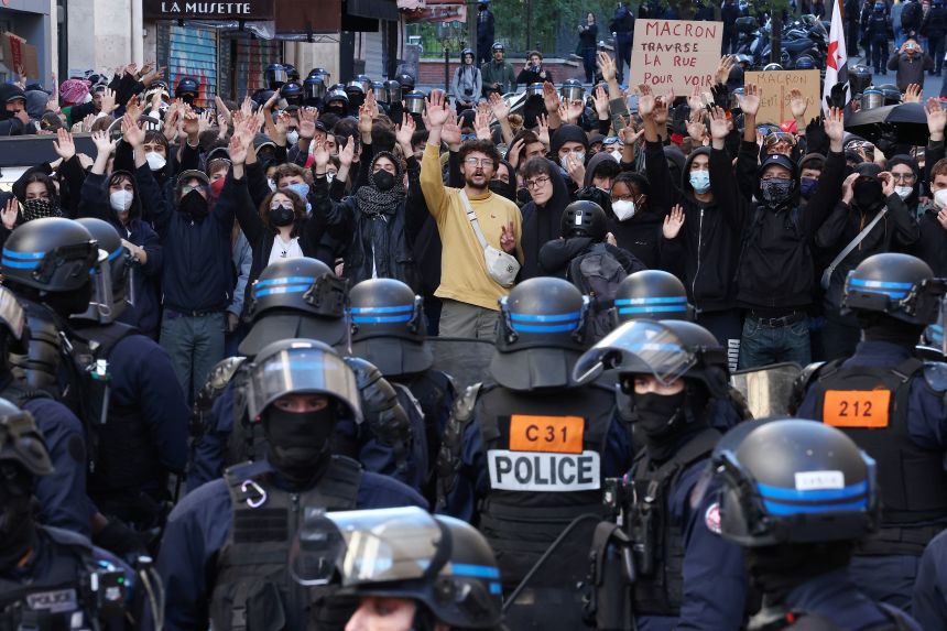 Masked protesters raise their arms as they face off with French riot police during a demonstration in a street near the Gare du Nord train station in Paris on Saturday, October 17, 2026.