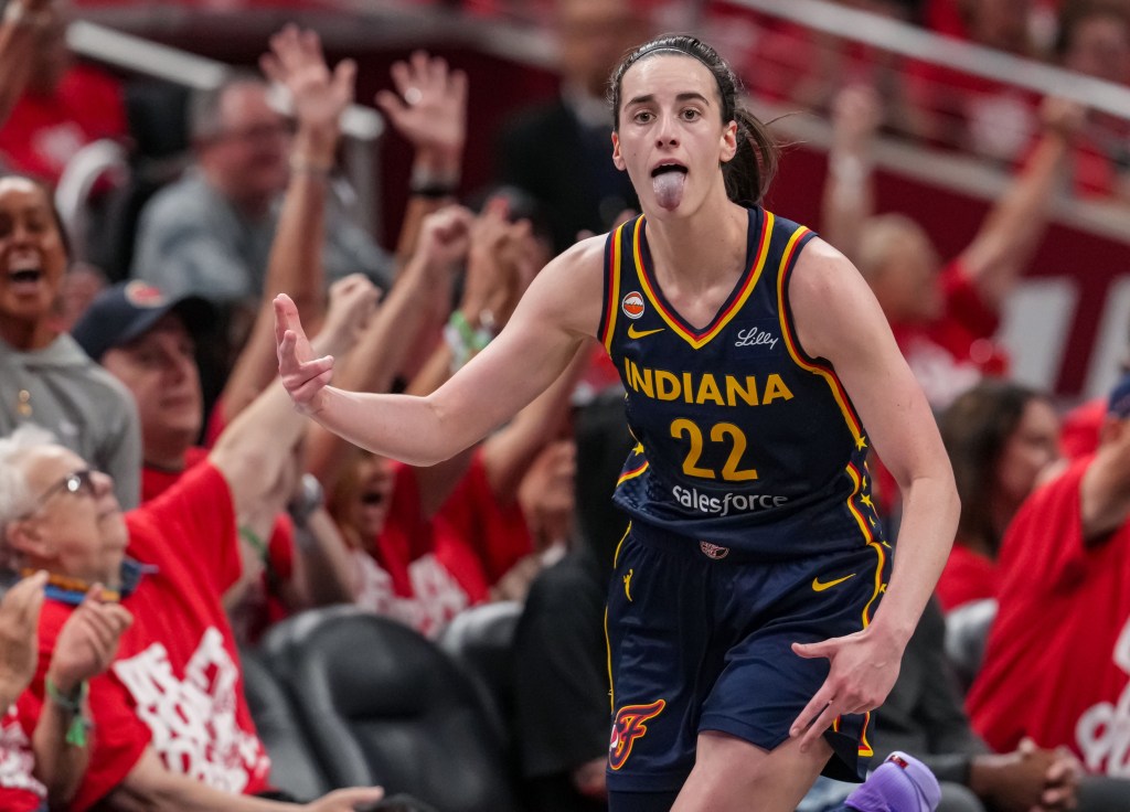 Indiana Fever guard Caitlin Clark celebrates with her tongue out in front of cheering fans.