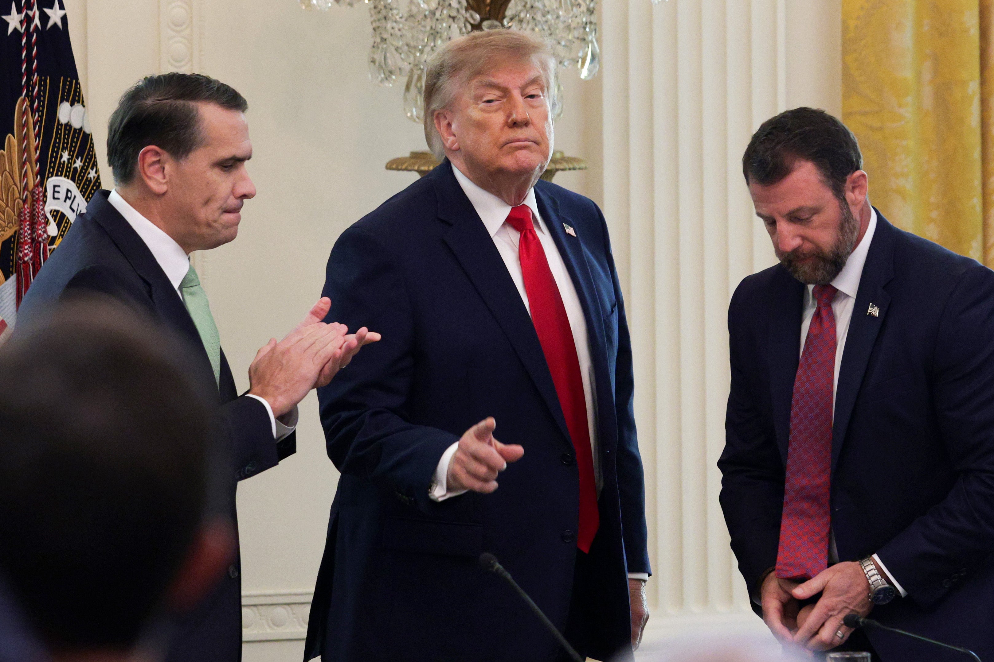 U.S. President Donald Trump (C) gestures as he departs with U.S. Attorney General Todd Blanche (L) and U.S. Secretary of Homeland Security Markwayne Mullin following a roundtable discussion on cybercrime in the East Room of the White House