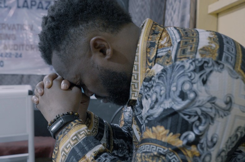 Samual Nnamdi rests his forehead on his knuckles as he prays.