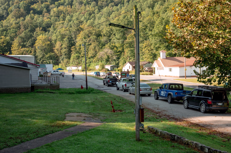 A line of cars wait to receive donated food during a weekly drive up food pantry at Dunlow Community Center