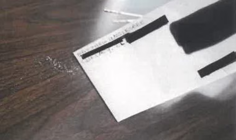 A white powder falls from a white envelope