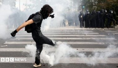 A masked student attempts to kick a tear gas canister amid clashes with French riot police during a demonstration by high school and university students, supported by teachers' union and school parents, in Paris as part of a nationwide day of protests and blockades, voicing anger over overcrowded classrooms, teacher shortages and dilapidated school buildings