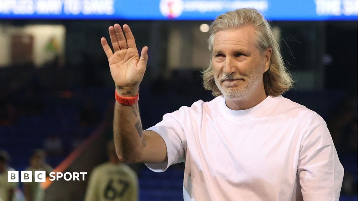 Robbie Savage in a white t-shirt watching Peterborough against Ipswich Under-21s from the touchline