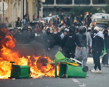 A student puts trashes into a fire as protesting students carry out blockading action near place de la Nation, in Paris.