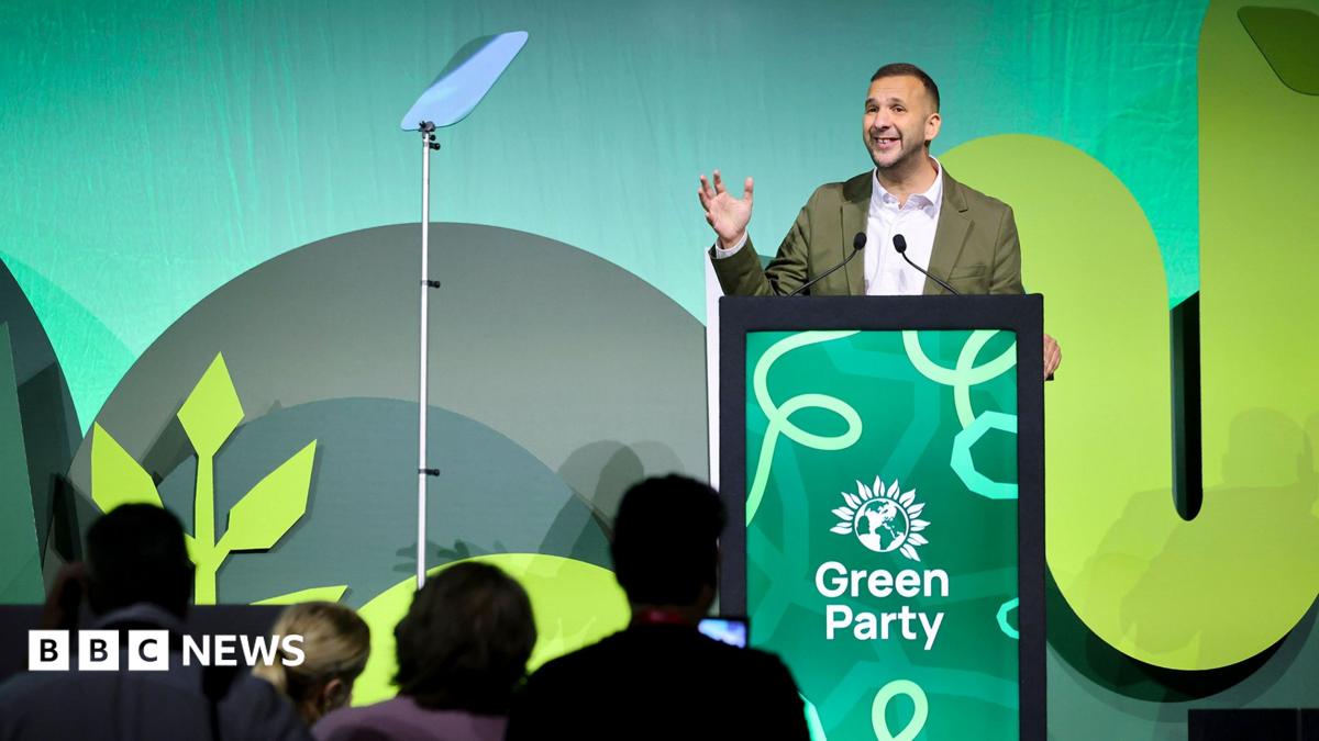 A woman takes a photo of sign advertising the Green Party conference.