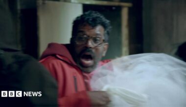 Romesh Ranganathan lets out a scream while holding a dead woman's wedding dress in the haunted cabin