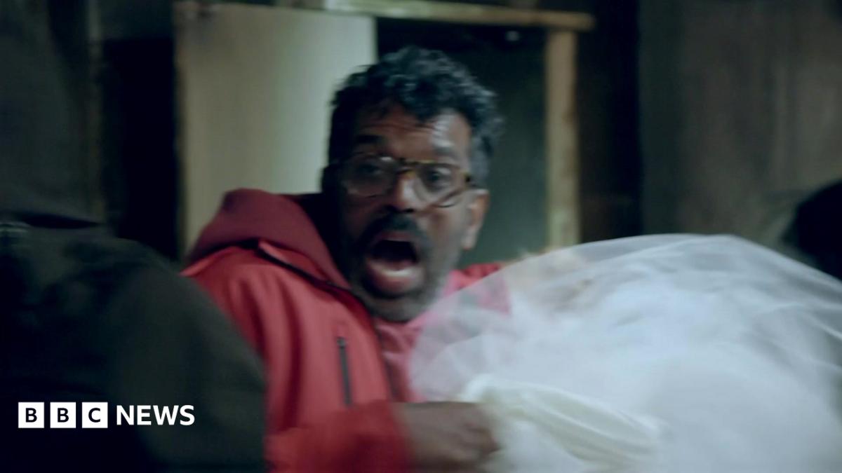 Romesh Ranganathan lets out a scream while holding a dead woman's wedding dress in the haunted cabin