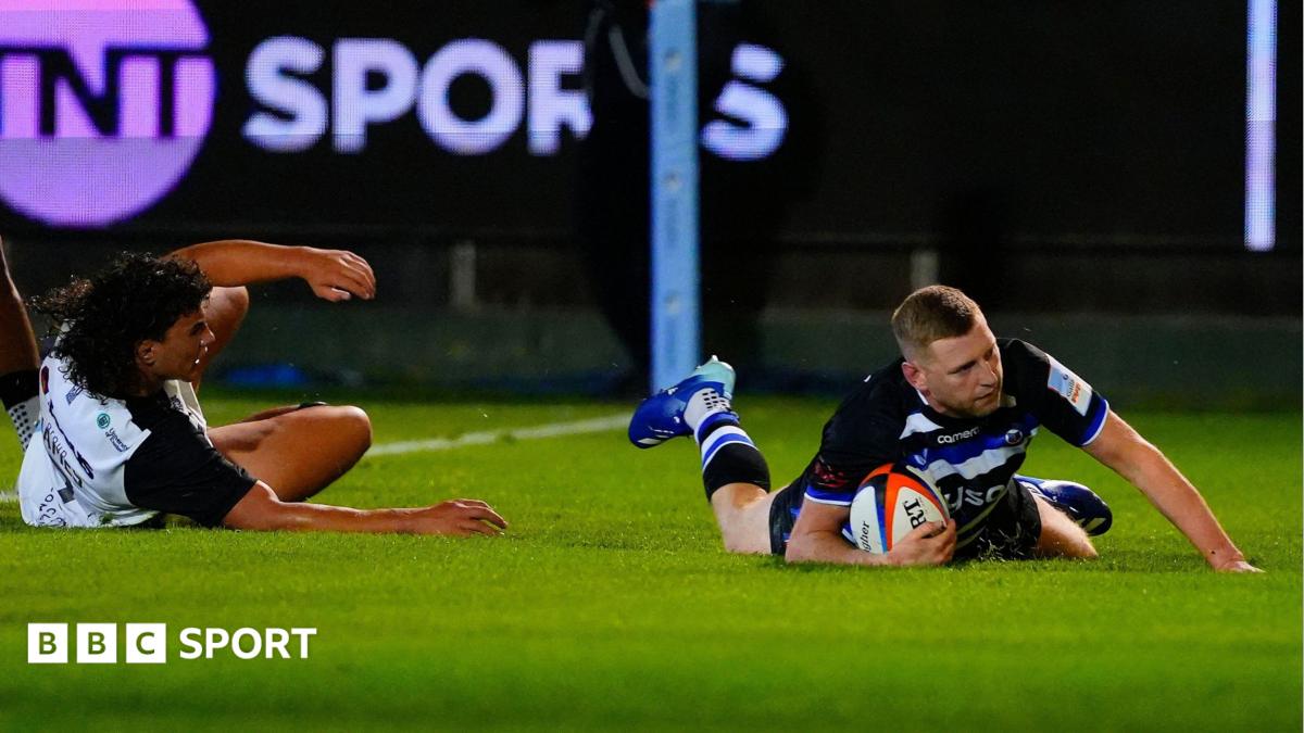 Finn Russell sliding over the line to score with Exeter's Kane James unable to stop him