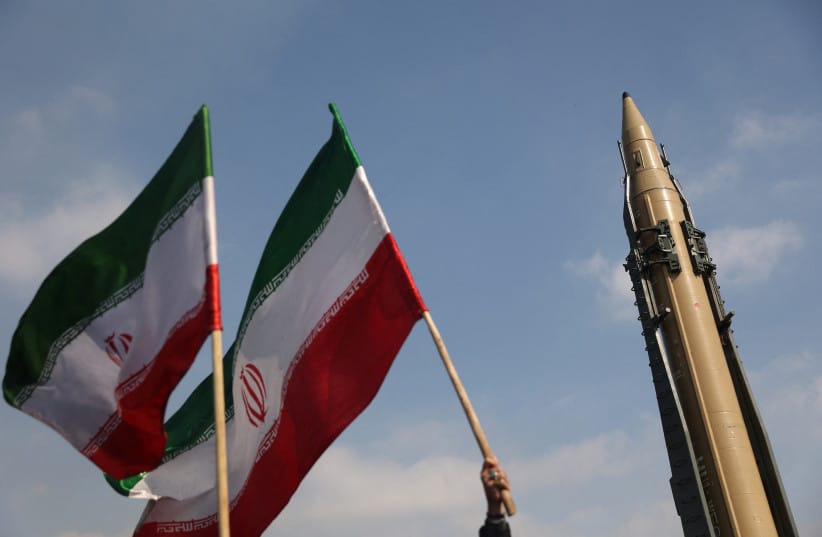 People wave flags next to an Iranian missile on display during the 46th anniversary of the Islamic Revolution in Tehran, Iran, February 10, 2025. (credit: MAJID ASGARIPOUR/WANA