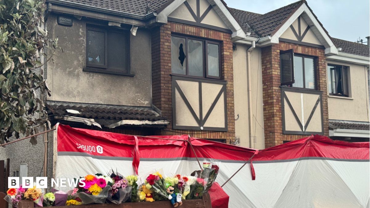 A house after a fire. Flowers and toys have been left outside.