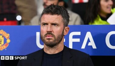 Michael Carrick, wearing a black T-shirt and black blazer, looks on from the dugout during a Champions League match