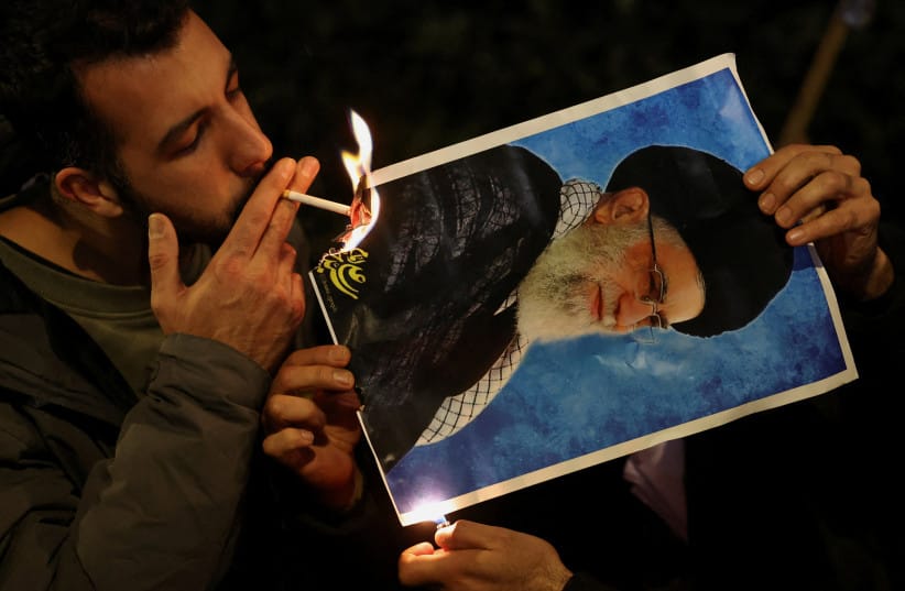 A demonstrator lights a cigarette with fire from a burning picture of Iran's Supreme Leader Ayatollah Ali Khamenei outside the Iranian embassy during a rally in support of nationwide protests in Iran, in London, Britain, January 12, 2026.