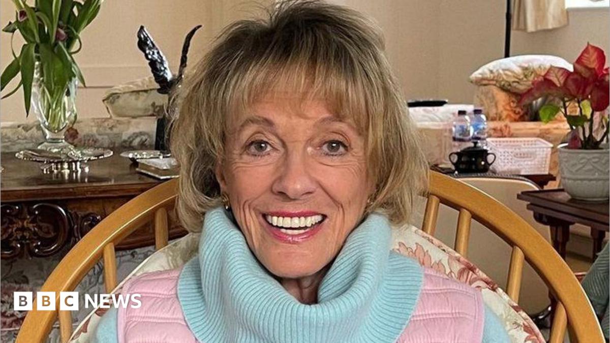 Esther Rantzen photographed towards the end of her life.  She is at home looking directly into camera and smiling.