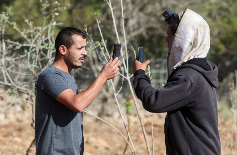 Yousef Hassan (L), whose house was encircled by militant settlers and later taken over by the military, films an Israeli settler (R) who entered the property of Palestinian-American Loui Ridi, in Kusra, in the West Bank, August 18, 2026.