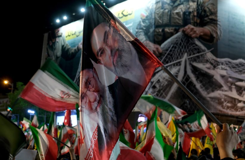Under a huge banner on the corner of Revolution Square with a message from IRGC that reads the Strait of Hormuz will remain closed, people holding Iranian flags and images of Mojtaba and Ali Khamenei the present and assassinated supreme leaders defy any negotiations with US; illustrative