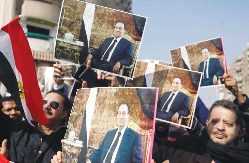 Supporters of Egyptian president Hosni Mubarak display his photo during his burial ceremony, east of Cairo, Feb. 2020.