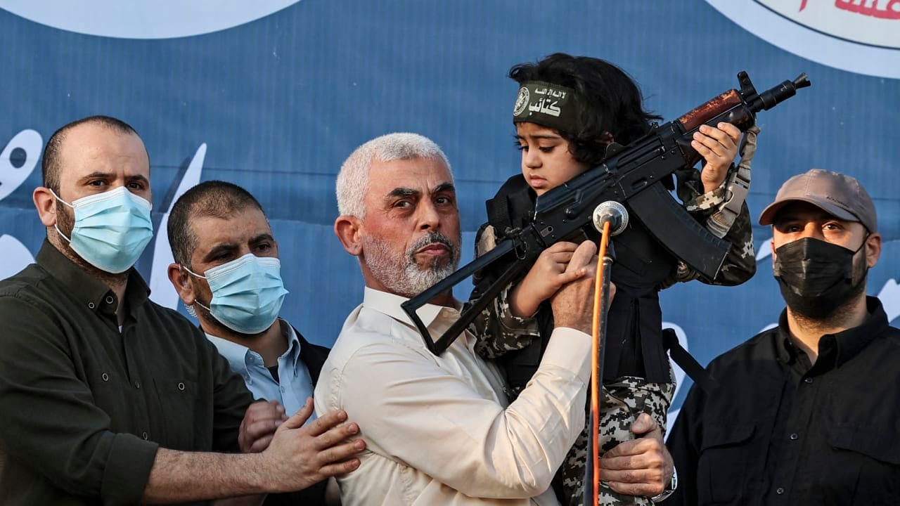 Hamas leader Yahya Sinwar holds the child of an Al-Qassam Brigades fighter, who was killed in the recent fighting with Israel, with a Kalashnikov rifle in his hand during a rally in Gaza City on May 24, 2021.