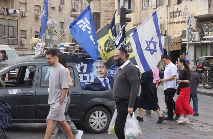 People walk past a vehicle displaying Likud campaign posters featuring Prime Minister Benjamin Netanyahu, in Jerusalem's Mahane Yehuda market, October 16, 2026