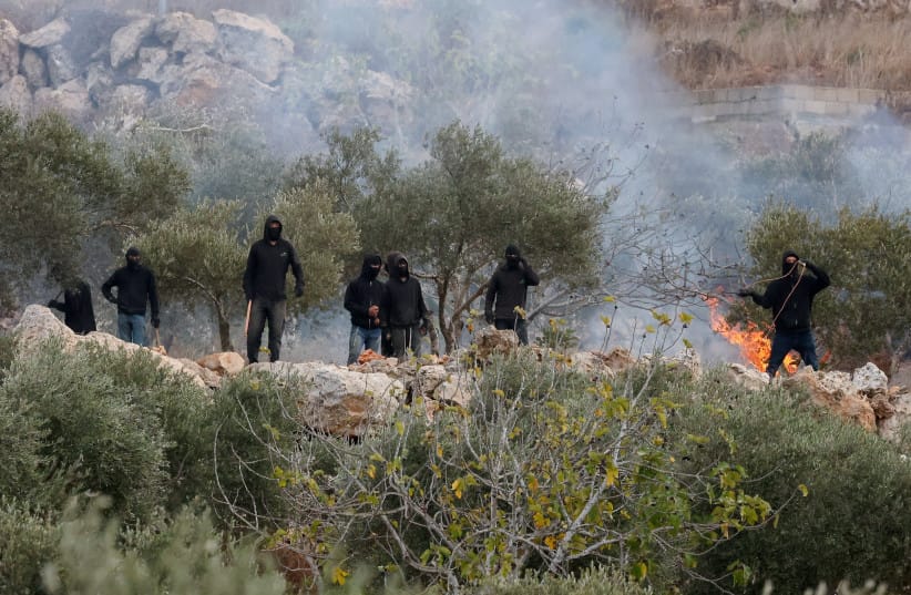 Israeli settlers next to a fire amid clashes with Palestinians during olive harvest in Abu Falah near Ramallah in the West Bank, October 16, 2026.