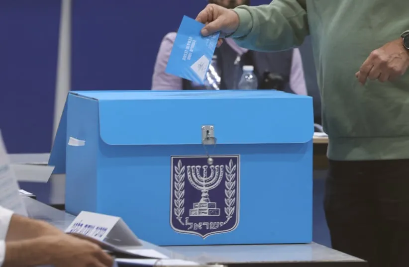 A voter places his ballot into a collection box during Israel's 26th Knesset elections, October 27, 2026.