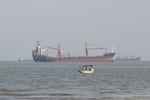 A boat floats as commercial vessels appear anchored in the Strait of Hormuz off Bandar Abbas, Iran, Tuesday, Oct. 13, 2026.