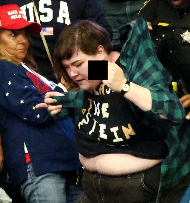 The protester being dragged out of the venue.