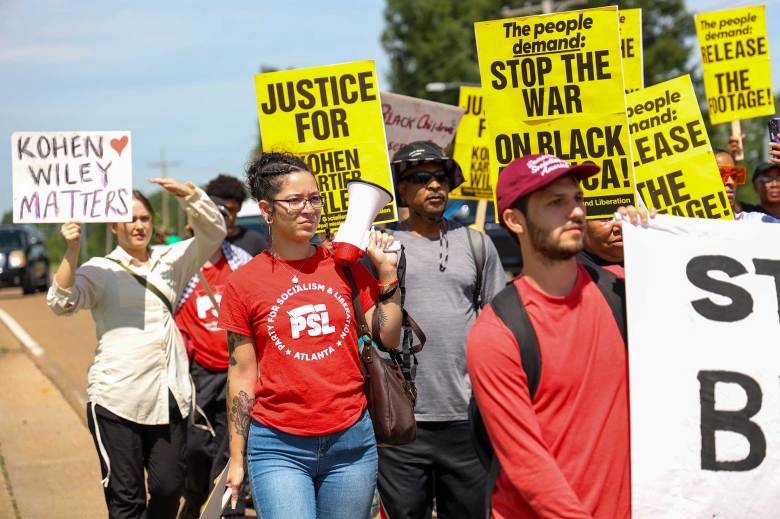 People march carrying signs down the street that say "Kohen Wiley Matters" and "Stop the War on Black America!"