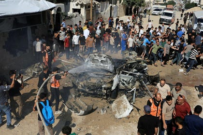 Palestinians gather around the remains of a vehicle after it was hit by an Israeli strike, in Gaza City, Thursday.