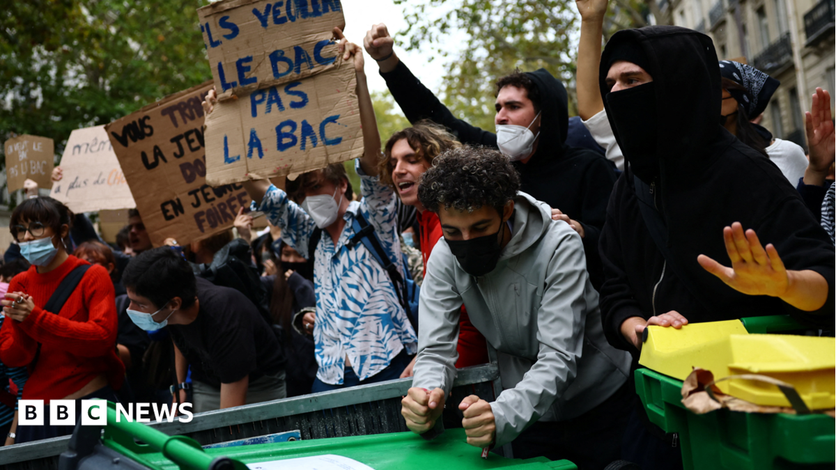 Protesters hold placards behind a barricade to block in Paris, 7 October