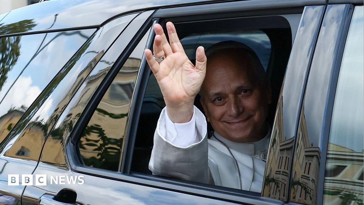Pope Leo XIV waves from the window of a car as he leaves Rome's Gemelli University Hospital.