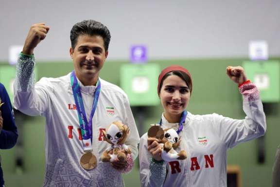 Hanieh Rostamian and Vahid Golkhandan celebrate after winning bronze for Iran in the mixed team shooting event at the 2026 Asian Games.