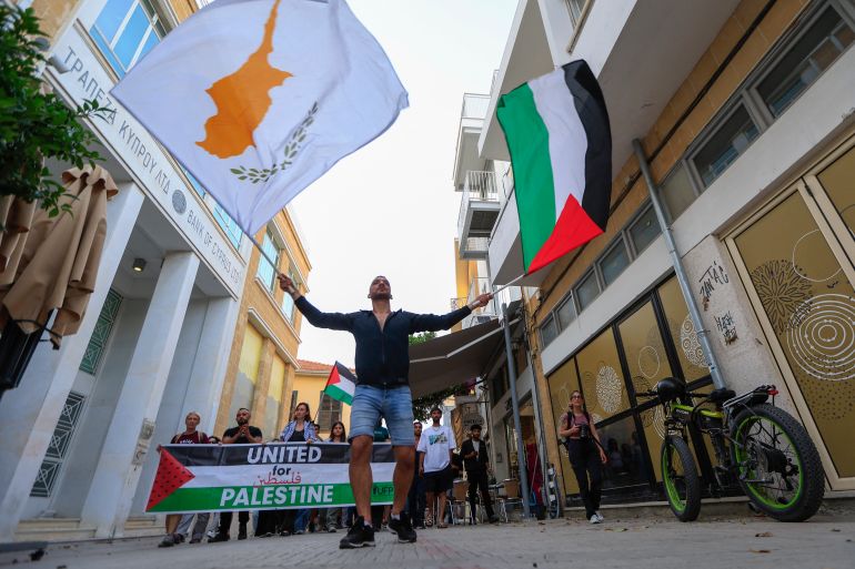 Activists lift flags of Cyprus and Palestine as they march in support of Palestinians in Nicosia