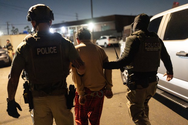 Homeland Security Investigations task force officers escort a suspect.