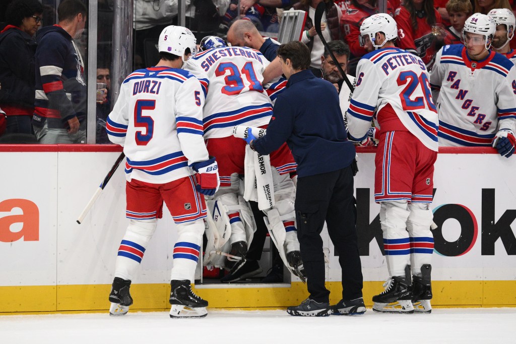 Igor Shesterkin, wearing number 31, is helped off the ice by team staff and teammates.