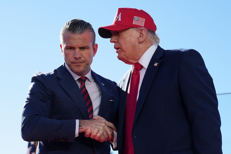 US Defense Secretary Pete Hegseth shakes hands with US President Donald Trump onstage during an event at Sparrows Point Shipyard, in Baltimore County, Maryland, October 6, 2026.