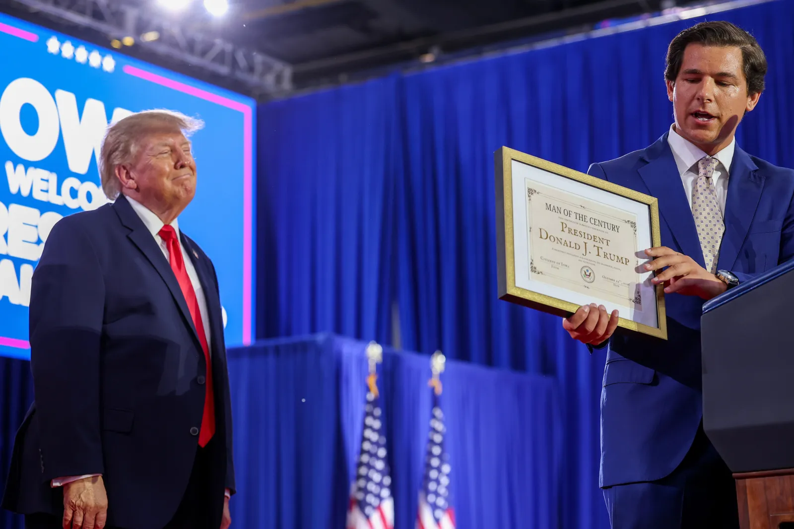 Iowa Republican House candidate Joe Mitchell (R) presents U.S. President Donald Trump (L) with a self-made "Man of the Century Award" during a rally at Sioux Gateway Airport on October 22, 2026, in Sioux City, Iowa.