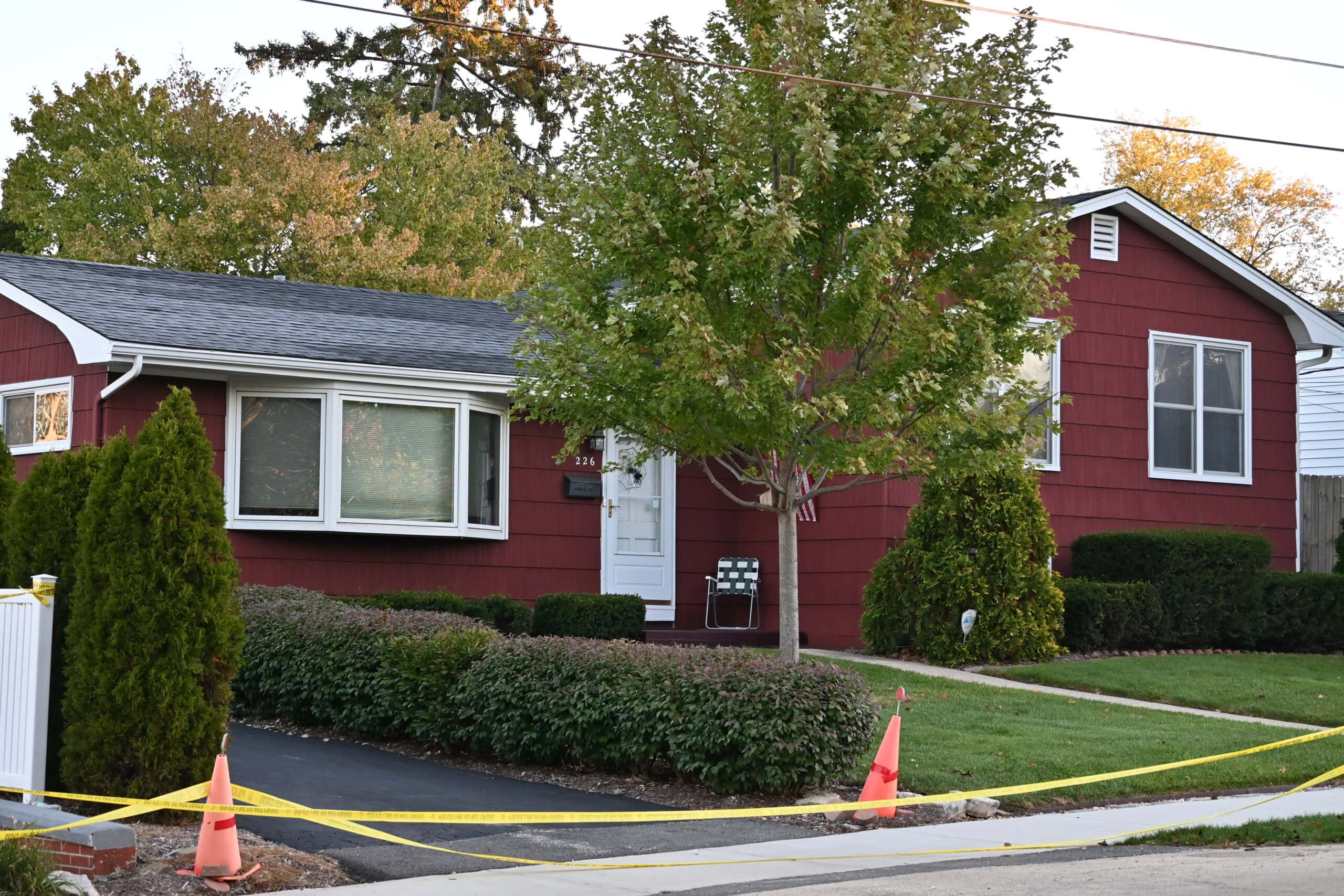 Crime scene tape and traffic cones in front of a red ranch home on Wellington Avenue in Mundelein