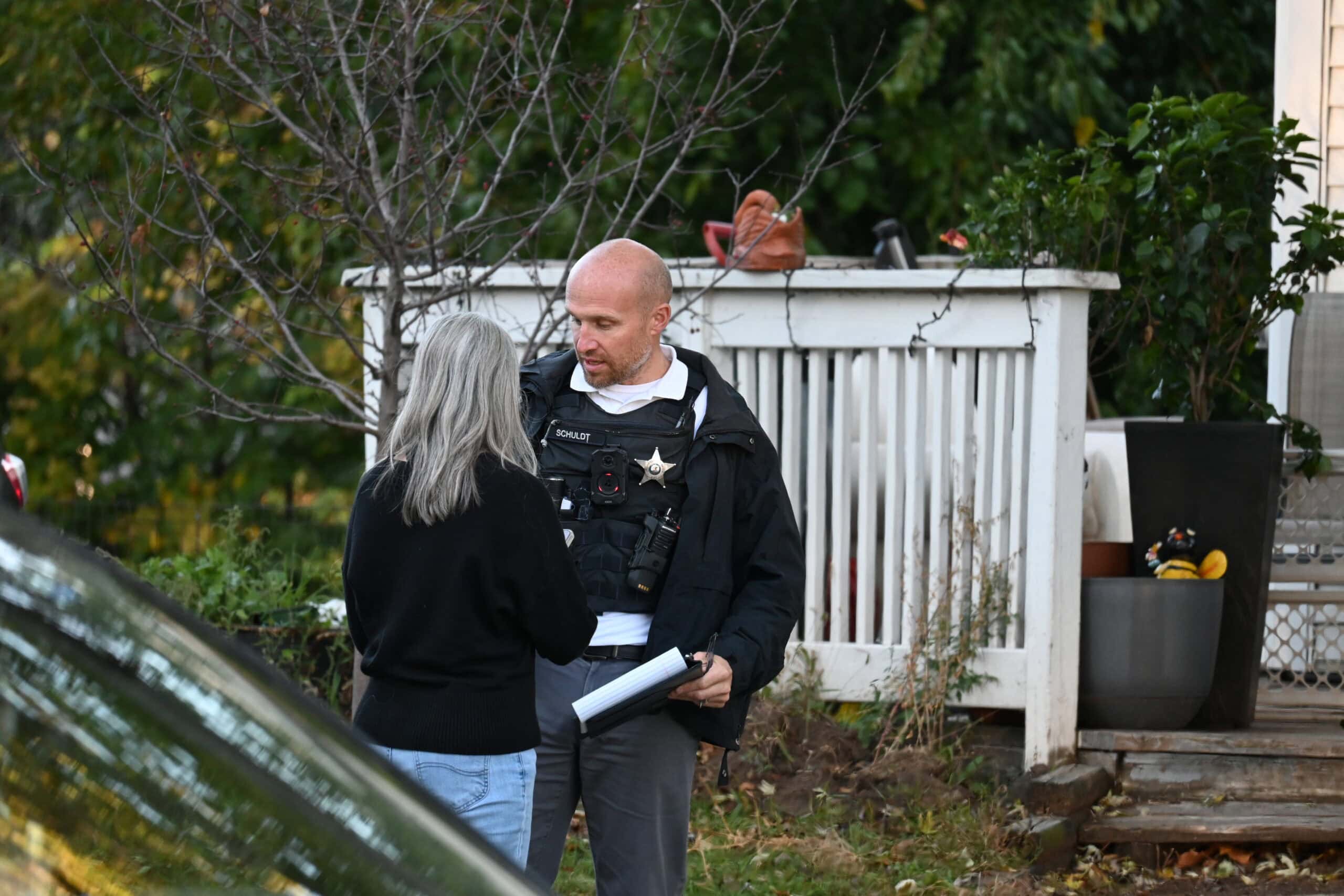 A Mundelein police officer holding a clipboard speaks with a woman outside a home