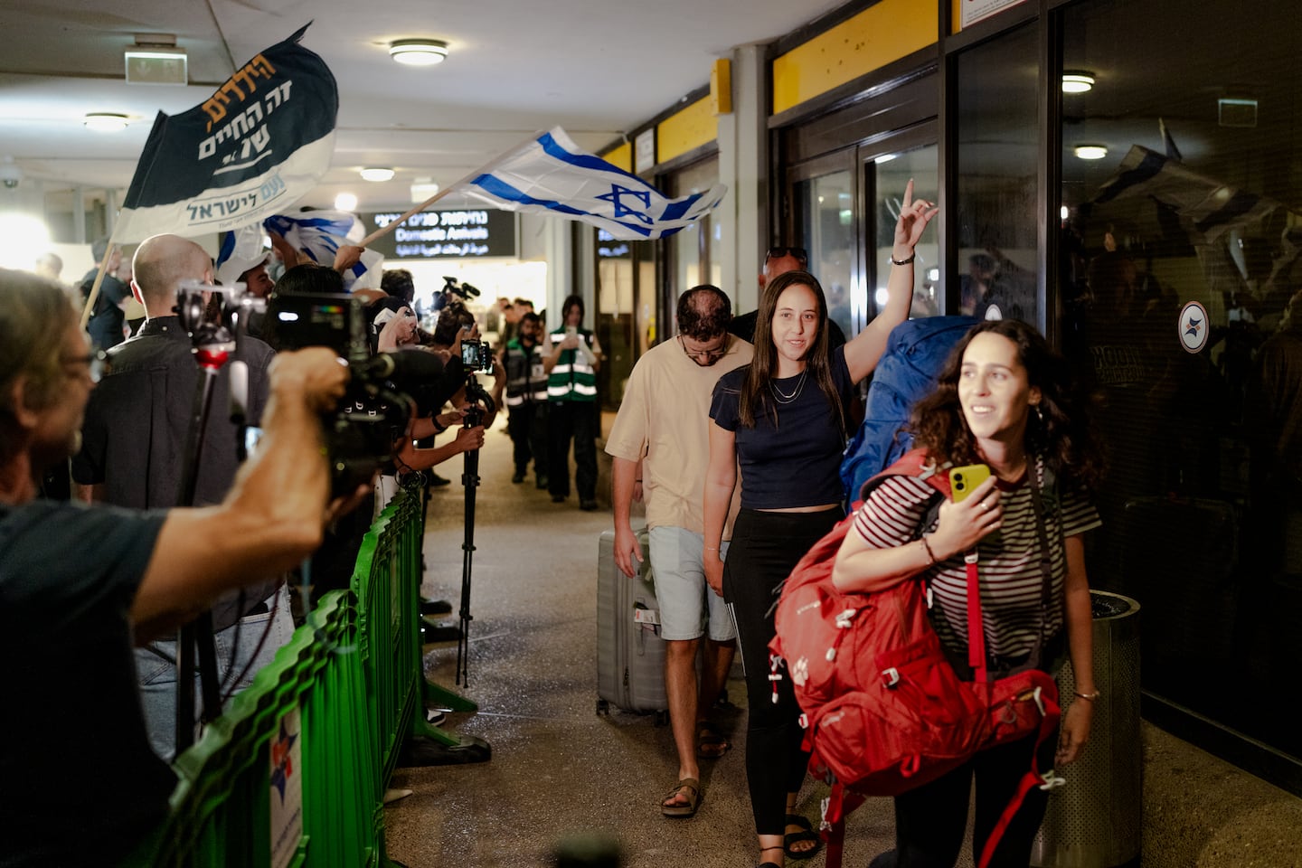 Passengers carried luggage through the terminal corridor lined with waiting crowds and flags upon arriving on a Flydubai retrieval flight at Ben Gurion Airport Wednesday.