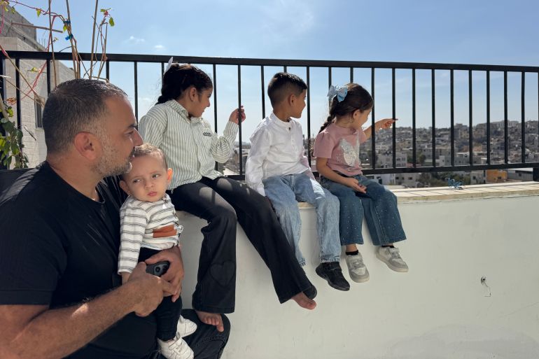 Fuad Abu Salam sits with his children in his rented apartment overlooking the Tulkarm camp gazing at their destroyed home Photo by Raghad Salameh-1791892542