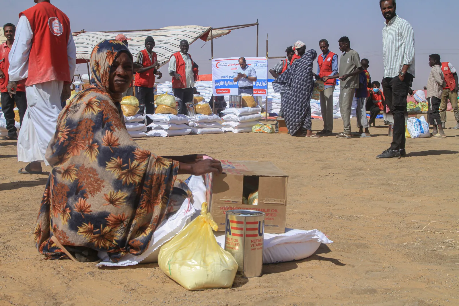 A Sudanese woman sits next to aid she received at the Al-Afad camp for displaced people in Al-Dabba, northern Sudan, on November 25, 2025.