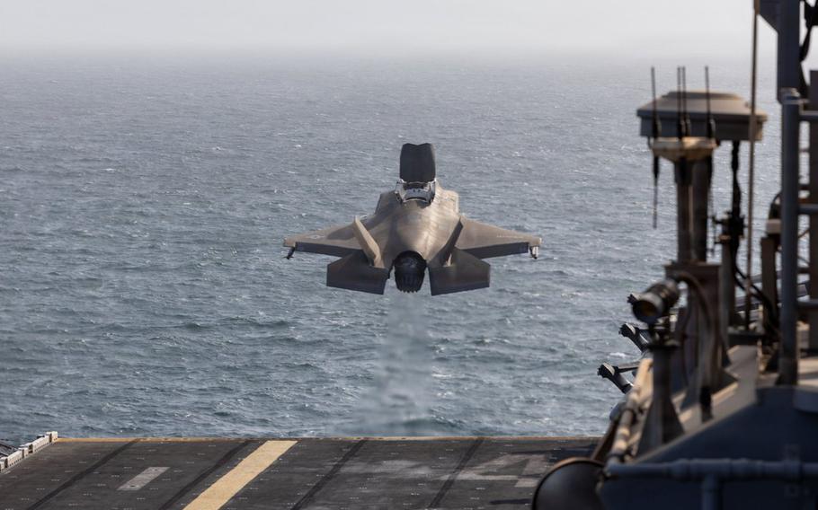 The fighter jet is airborne, with the flight deck below and the open sea ahead.