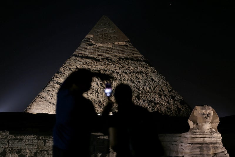 Tourists take photos of lit up Giza Pyramids and the Sphinx during the celebration of World Tourism Day at Giza, on the outskirts of Cairo, Egypt, September 27, 2024.