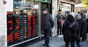 An elderly Iranian man studies dollar and euro rates outside a Tehran currency exchange